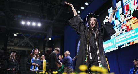 A woman graduate walks across stage at commencement