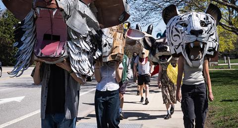 Students wearing large masks walk in a campus parade