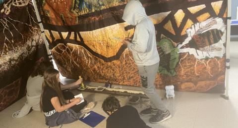 Three middle schoolers work against a backdrop of soils