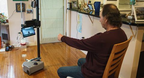 Brian Marquis works out with Robbie, a robot designed at UNH to aid people with Alzheimer’s or other forms of dementia