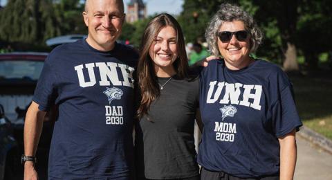 A female student stands between her parents on move-in day
