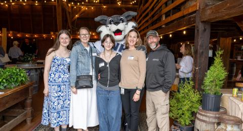 Five guests pose with Wild E Cat mascot in a barn