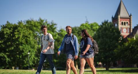 Three students walk with Thompson Hall visible in the background