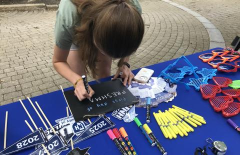 First-year student writing on chalkboard at First Day of School Photos event