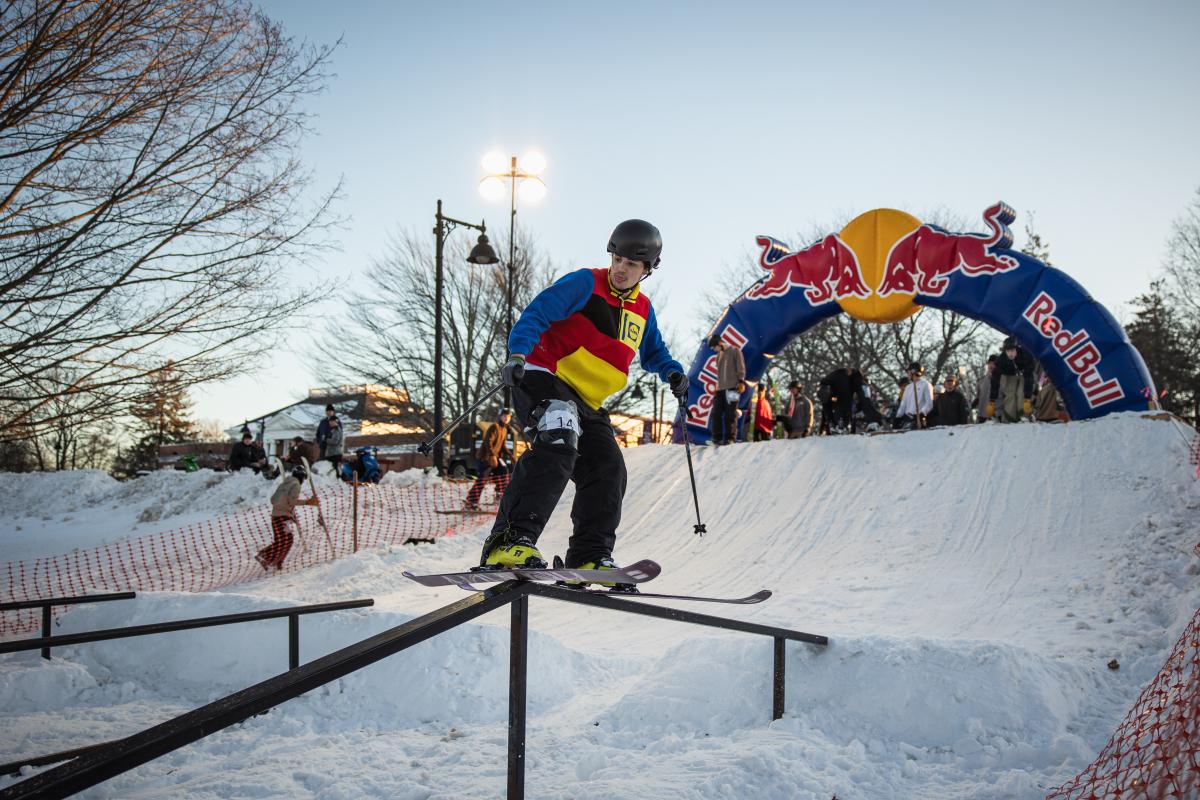 A skier slides sideways along a rail