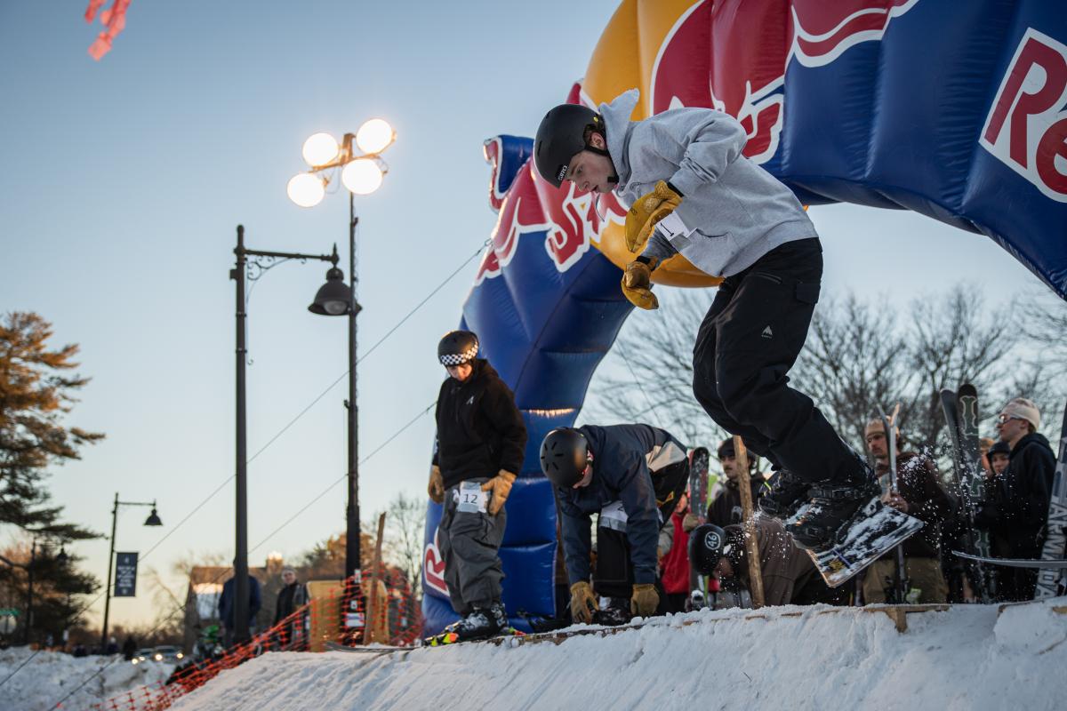 A snowboarder hops into the air as he is about to take off down a hill