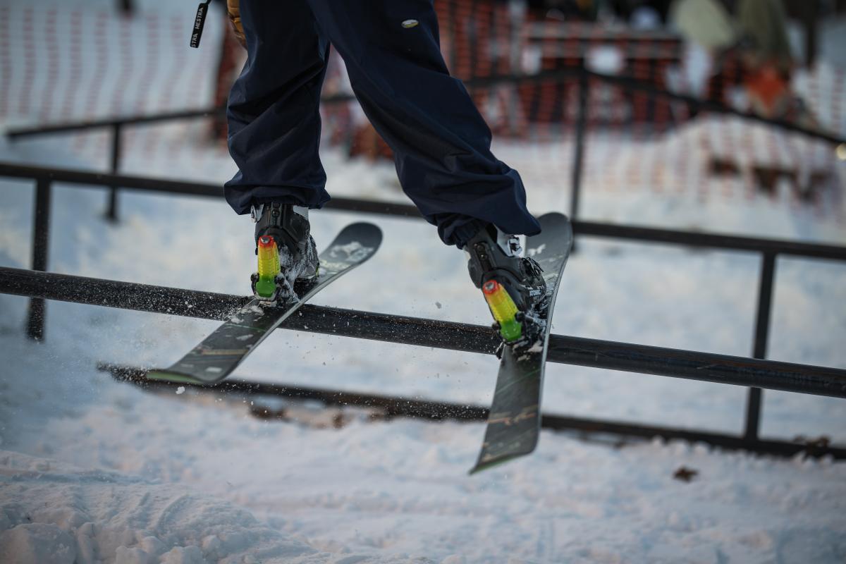 A close up of two skis sliding along a rail