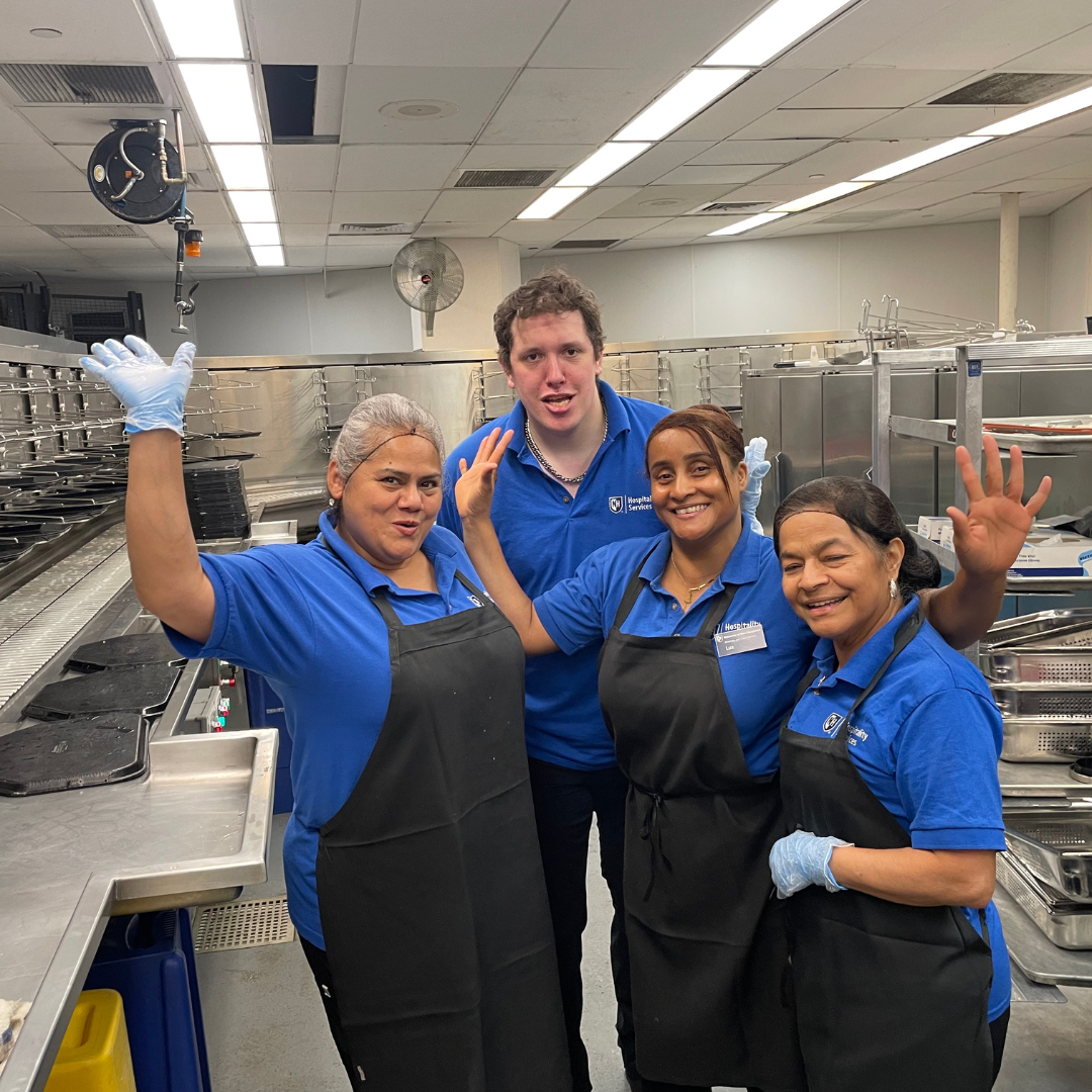 people in a kitchen smiling with hands raised 