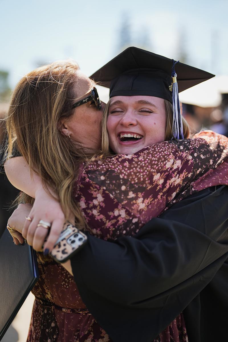 A woman graduate hugs someone after commencement