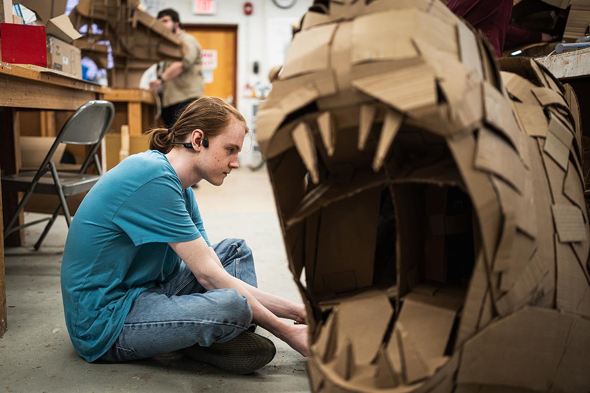 A student works on a cardboard mask during sculpture class