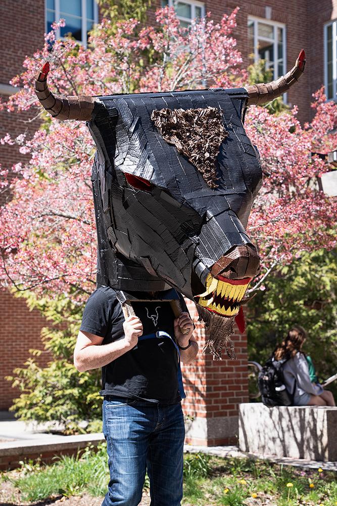 A student wears a large mask created in their sculpture class during a campus parade
