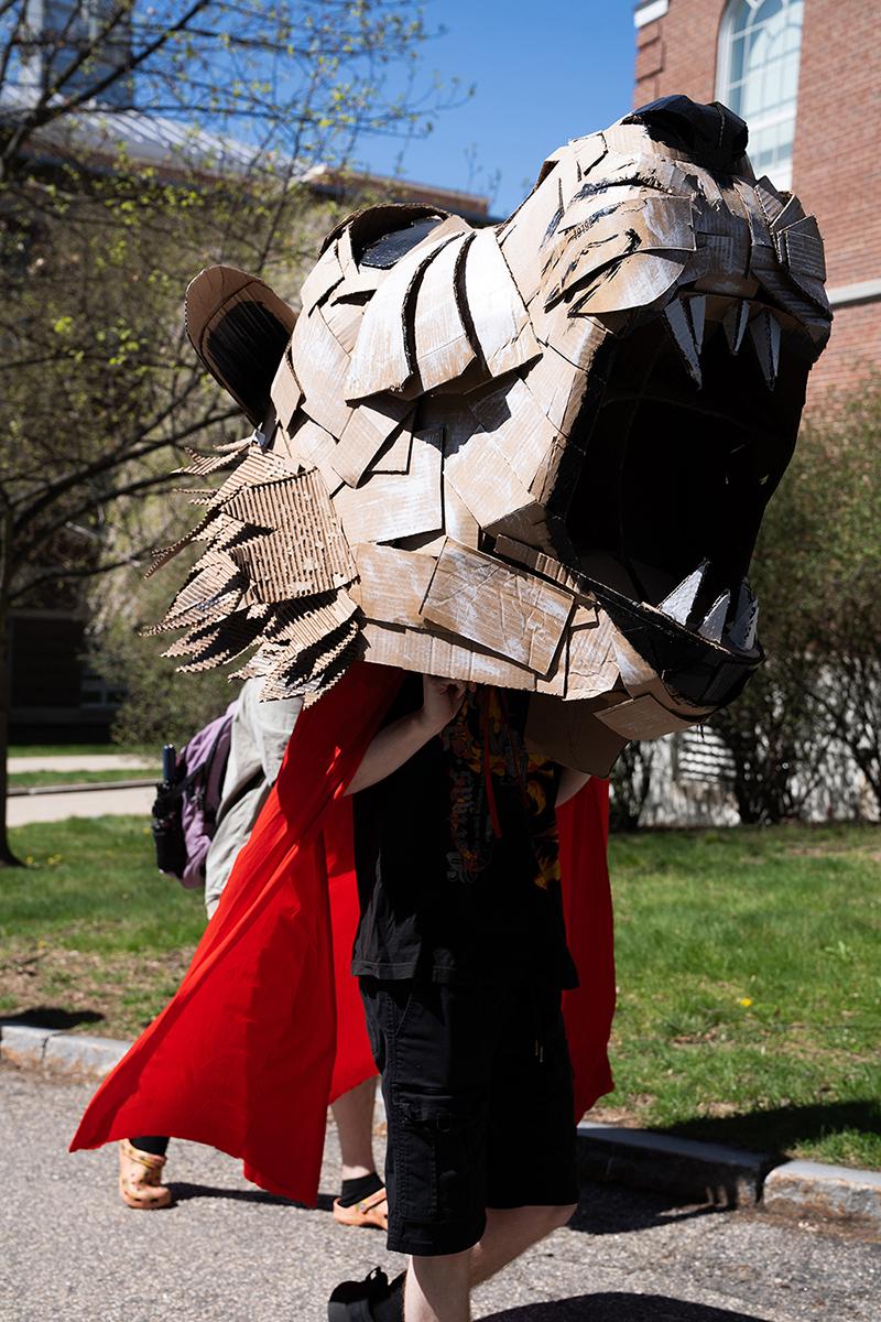 A student wears a large mask created in their sculpture class during a campus parade