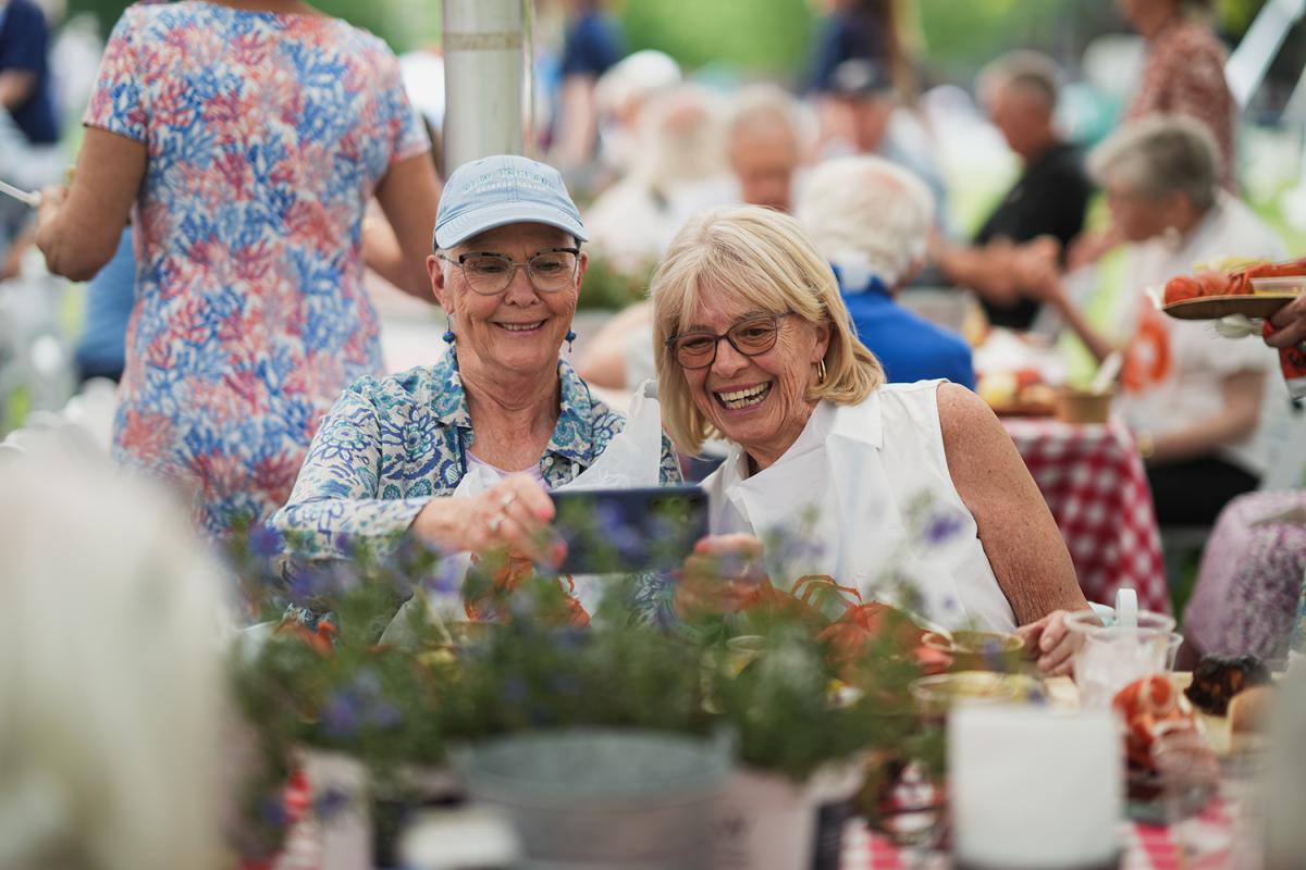 Two women sitting at a table take a picture together at reunion