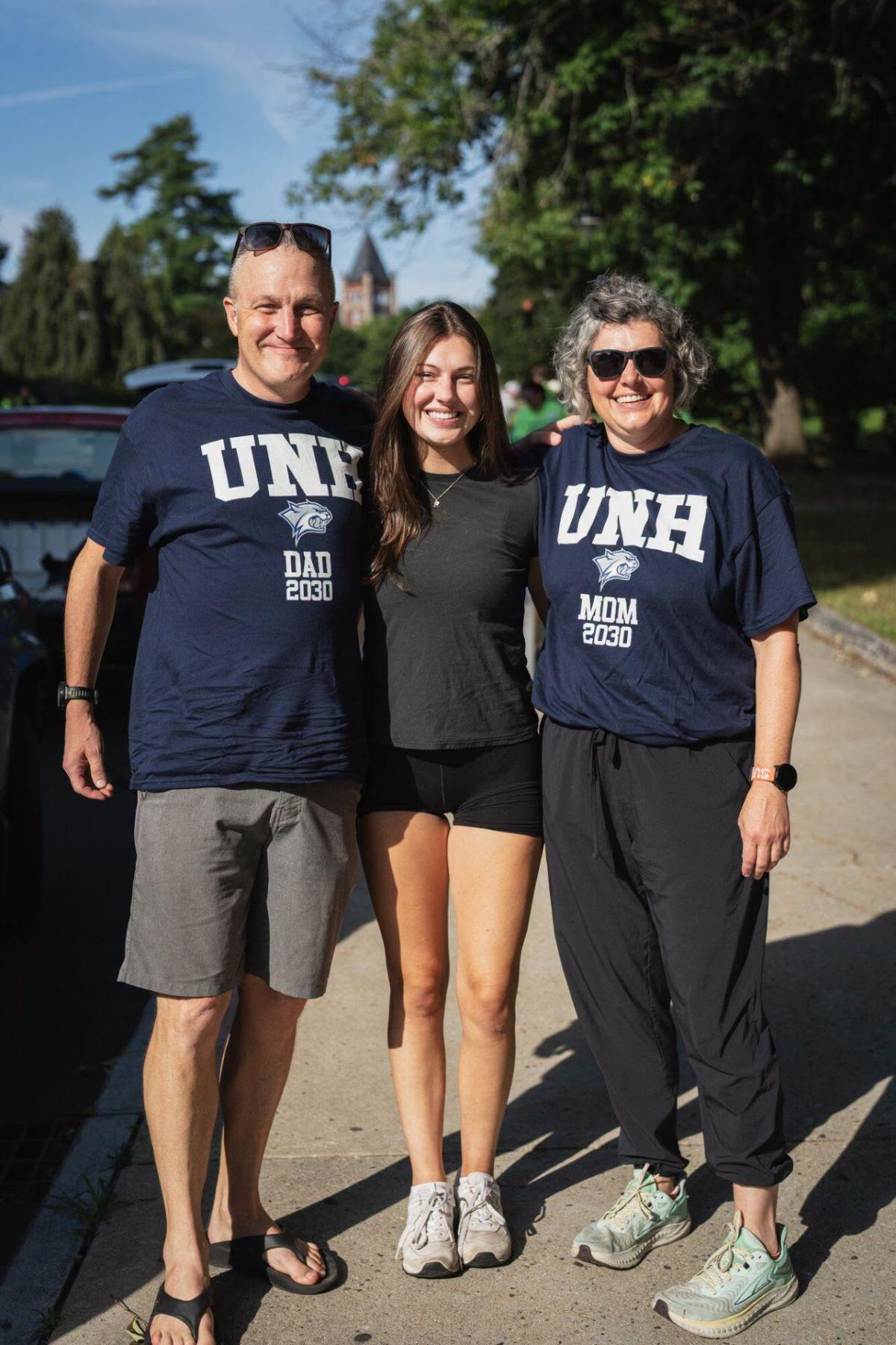 A student stands between her parents on move-in day