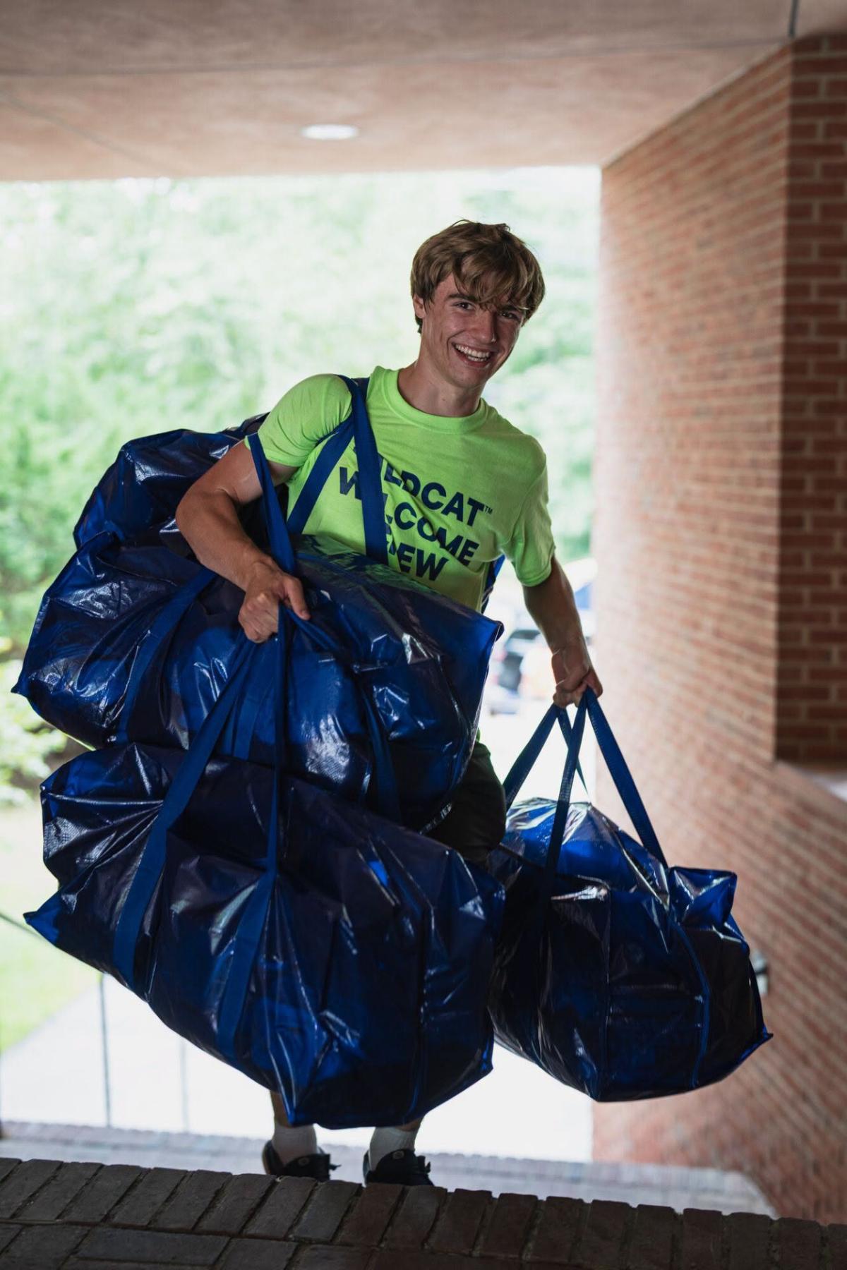 Volunteer carries three large duffel bags on move-in day