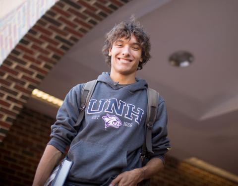 Male UNH Undergraduate Student smiling and wearing a backpack 