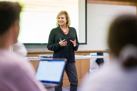 dynamic teacher presenting information in a classroom with a whiteboard in the background