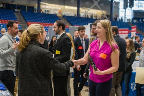 Students and alumni greeting potential employers at a career fair