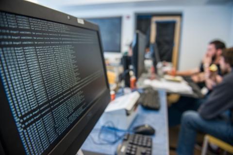 A large monitor in a UNH classroom showing rows of code and data