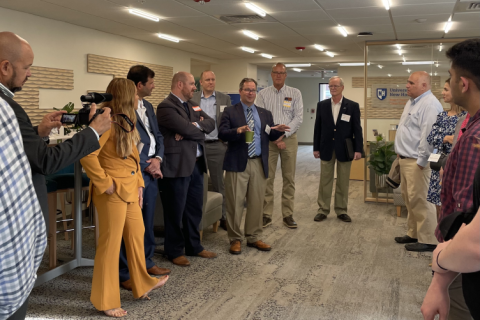 A UNH and business partnership meet and greet, people in suits with name tags in a campus room.