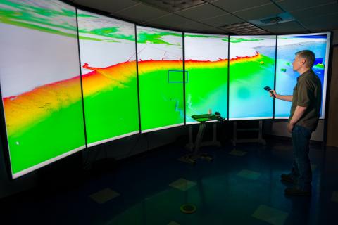 Presenter at a surround-screen digital map showing topography.