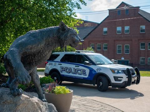 UNH Wildcat statue with a campus police car behind it