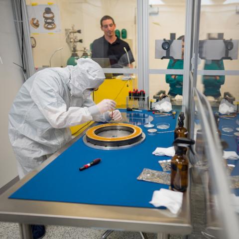 Researcher in protective suit works on scientific equipment