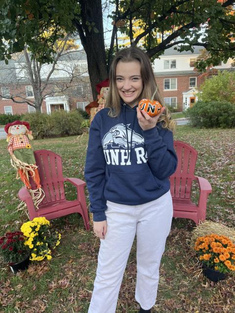 Student holding a small pumpkin