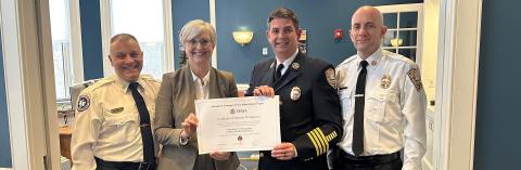 three firemen standing with a woman holding up a certificate