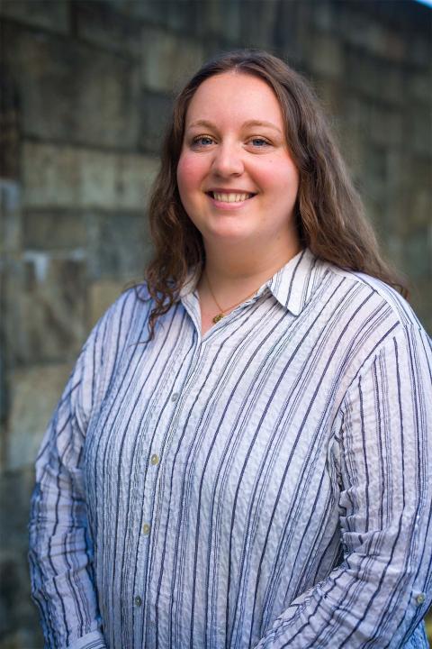 Master of Science in Nutrition student Elise Evans. Elise has white skin. She has shoulder-length dark brown hair. She wears a button shirt with dark and light blue stripes.