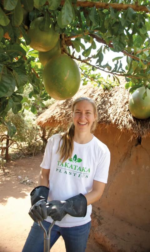 A woman in a white T-shirt stands in front of trees in Africa