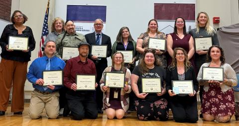 A group of people holding certificates to celebrate graduation from the FELEIA Academy gather for a photo