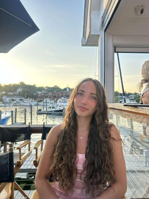 person outside with a dock, boats and water in the background