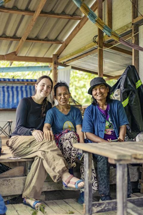 Three people seated inside on a bench with a table in the foreground