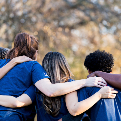 a group of people embracing each other, shown from behind