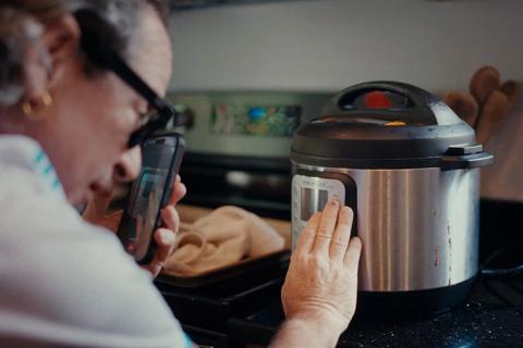 A woman uses a phone to help operate a cooking appliance
