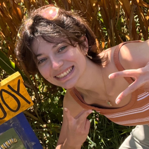 Person outside smiling and holding up two fingers in each hand