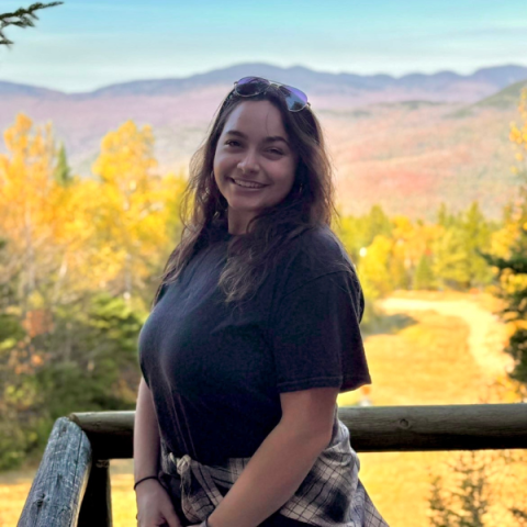 person standing outside with fall foliage and mountains in the background
