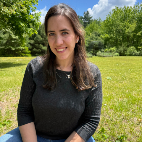 person outside sitting on lawn with trees in the background
