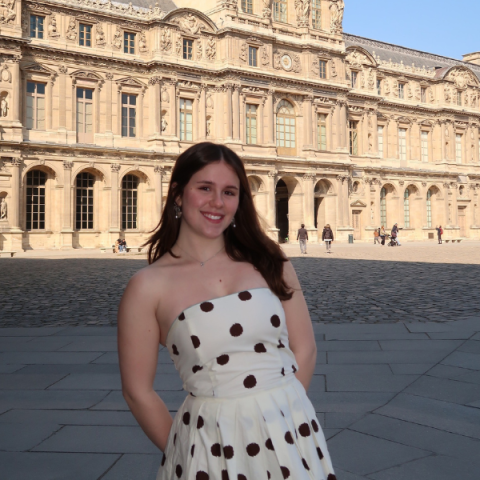 person standing outside with a large building in the background