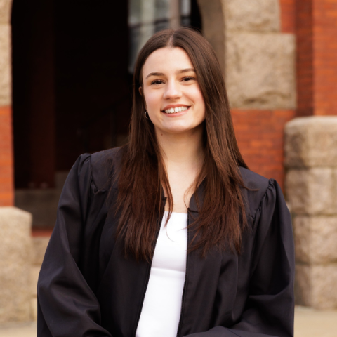 person smiling in front of a brick and stone building