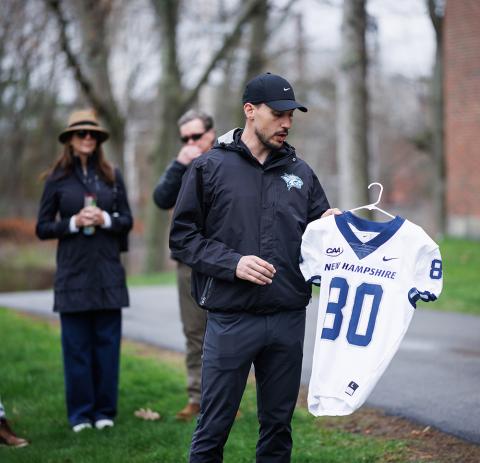 UNH football coach Sean Goldrich holds Todd Walker's football jersey