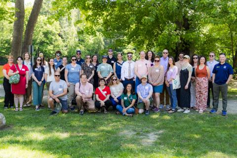 A large group of people poses for a photo in a park