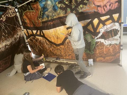 Three middle schoolers work against a backdrop of soils