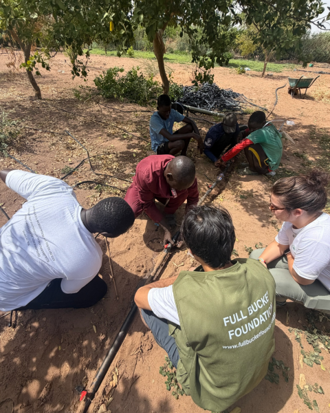 group of people outside in a group working the soil