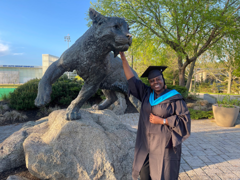 MPA alum Chioma Agbahiwe touching the Wildcat's nose after commencement