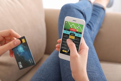 Stock image of a person placing a bet on their phone.