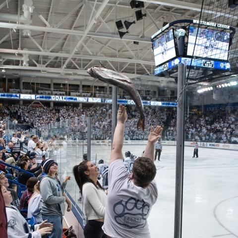 student tossing fish on to the ice at hockey game