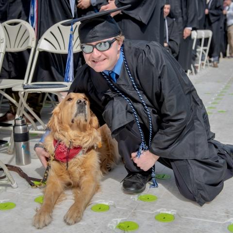 student with service dog at commencement