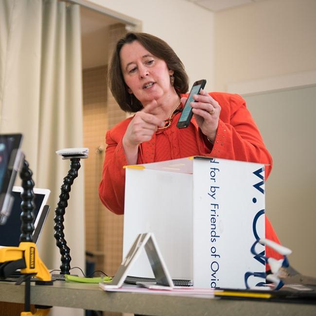 Occupational Therapist Holding a phone over a box